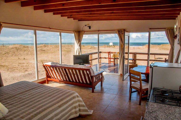 Playa Loft: loft con cama, sillón y ventanales al mar