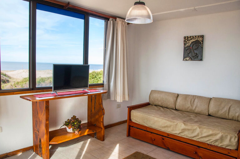 Sol G y E: sillón y TV frente a la ventana al mar